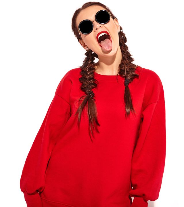 young happy smiling woman model with bright makeup and colorful lips with two horns and sunglasses in summer red clothes isolated on white. Going crazy and showing her tongue