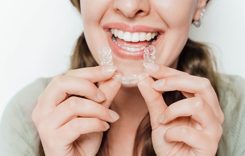 Smiling Woman Holding Clear Teeth Aligner